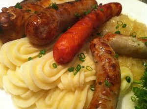 Assorted German grilled sausages with sauerkraut and mashed potatoes.