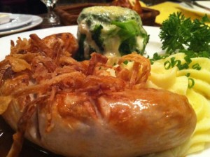 German veal sausage with mashed potatoes and a fat stack of broccoli and cheese.